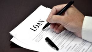 Image of a hand signing a document with loan as the title