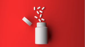 a white bottle juxtaposed on a red background with white pills spilling out of it