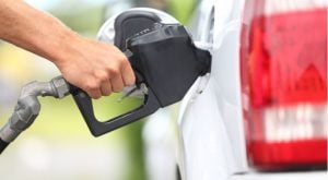 A photo showing a hand putting a gas pump nozzle into a car.