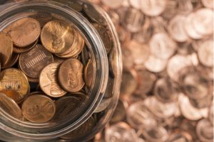 a jar filled with pennies on a table covered in pennies to represent penny stocks