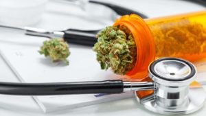 Marijuana falls from a prescription container next to a stethoscope