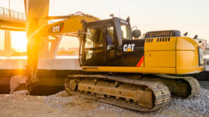Caterpillar (CAT) excavator vehicle backlit by sunset