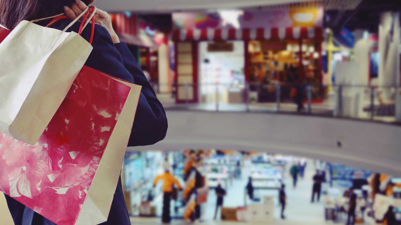 a person standing in a shopping mall with a bag in their hand representing May CPI data.