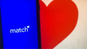 the match group (MTCH) logo displayed on a phone screen next to a heart