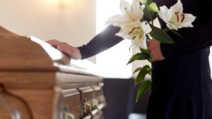 mourner laying their hand on a casket