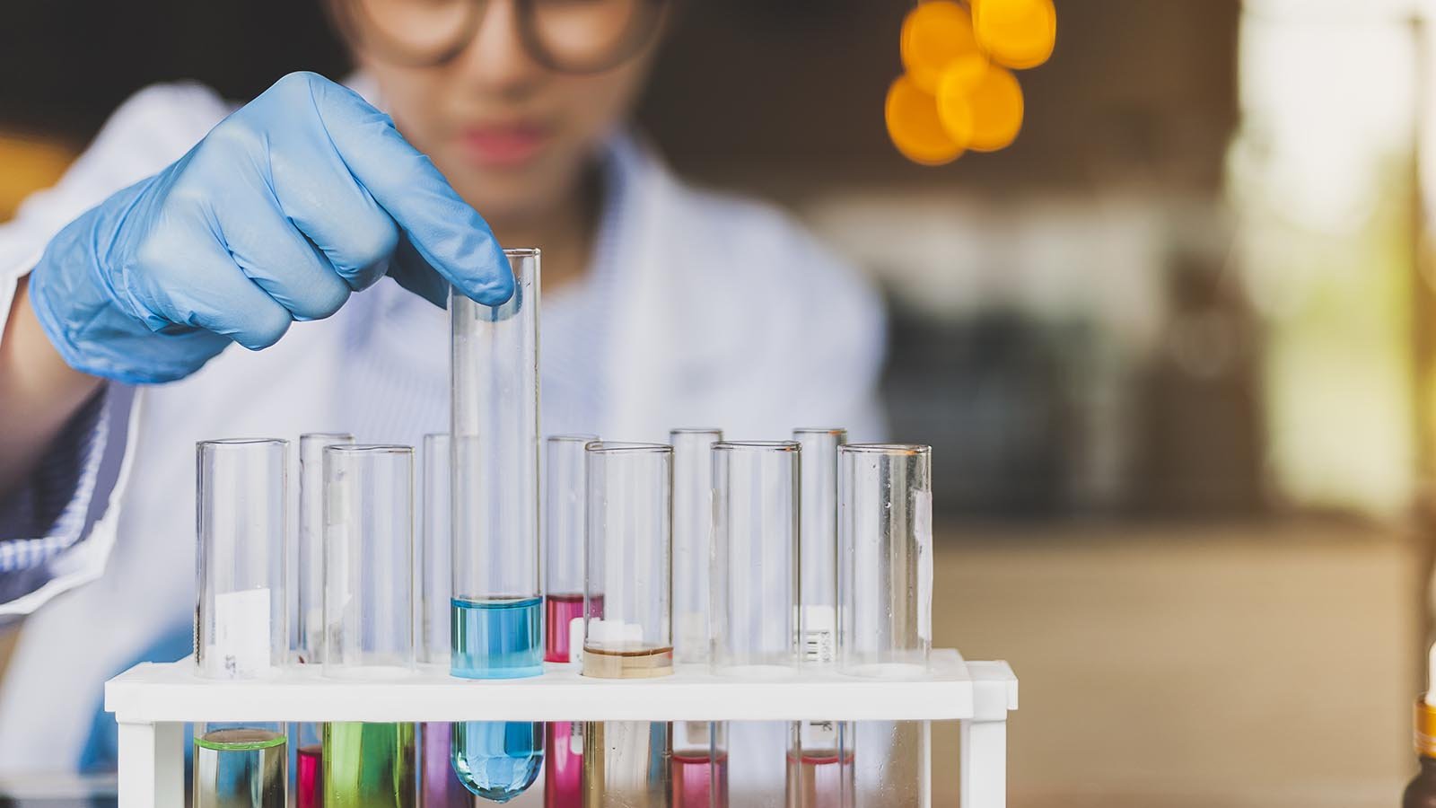 A scientist holds a test tube while it is in a container