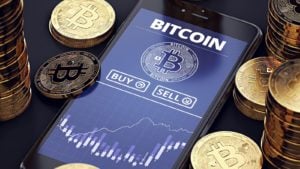 crypto Smartphone with Bitcoin chart on-screen among piles of Bitcoins