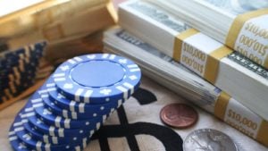 Blue poker chips stacked next to three stacks of $100 bills representing blue chip stocks