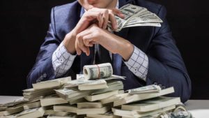 Man holding cash behind a pile of cash