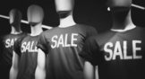 a black and white photograph of manikins wearing shirts that say sale on them