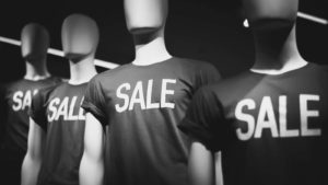 a black and white photograph of manikins wearing shirts that say sale on them