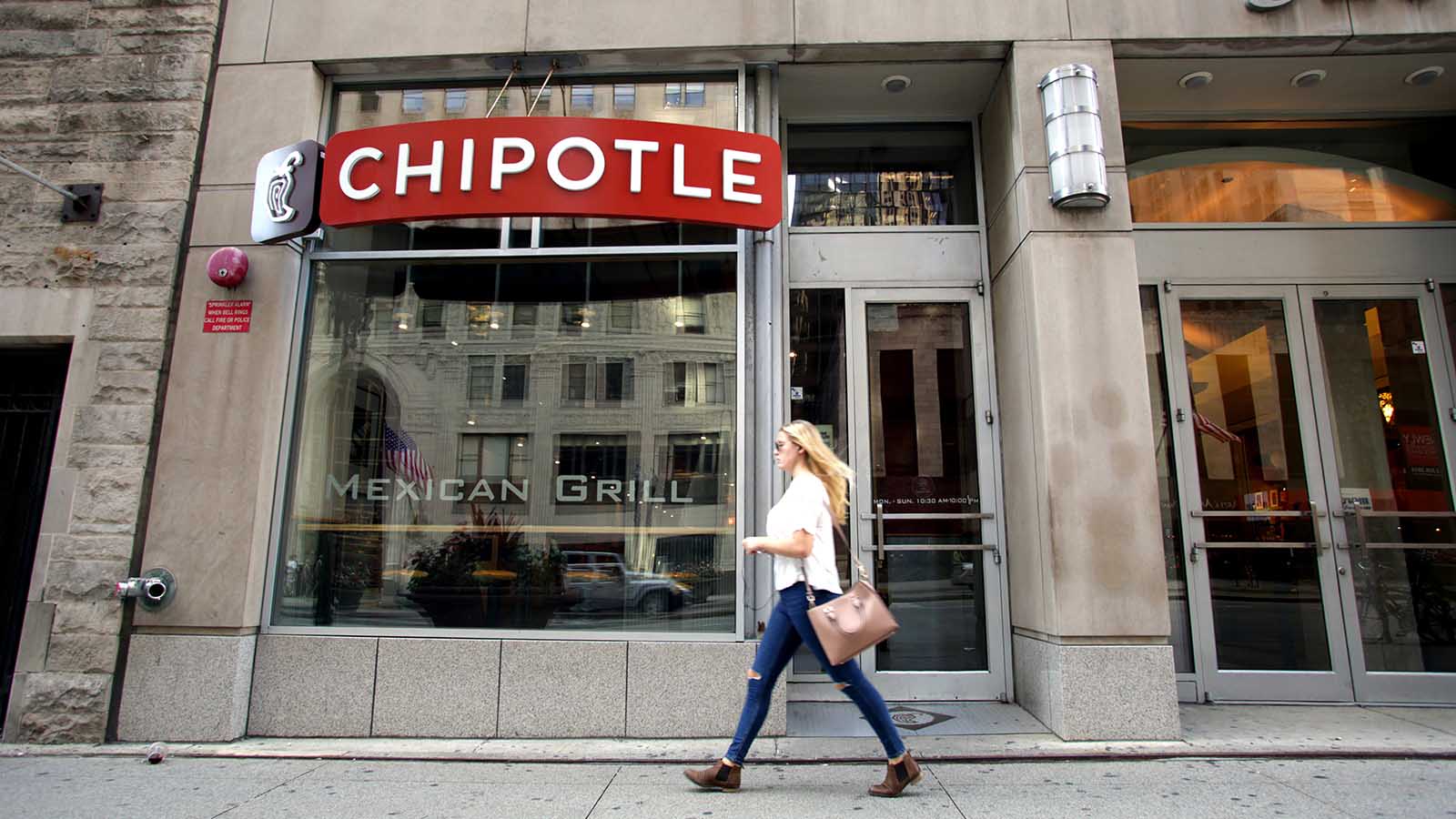 a pedestrian walks past a Chipotle (CMG stock)