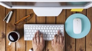 overhead shot of hands on a white keyboard