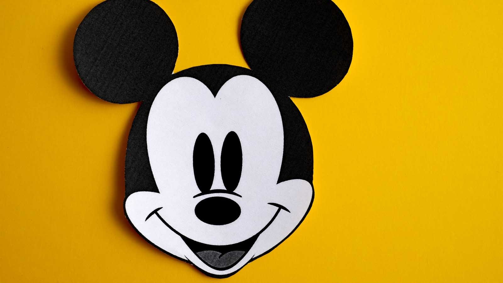 an image of mickey mouse on a yellow background to represent disney (DIS)