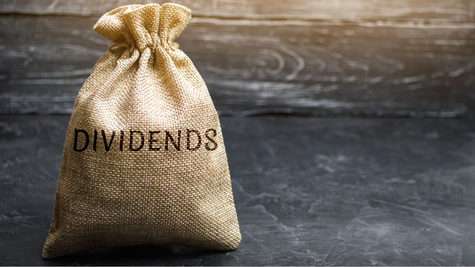 a bag on a table with the word "dividends" on it. represent dividend stocks to buy