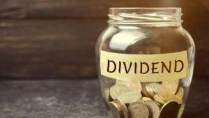 Glass jar of coins marked "dividends" to represent dividend stocks. stocks with dividends