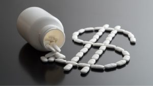dollar sign written with pills spilled from a medicine bottle. millionaire maker drug stocks