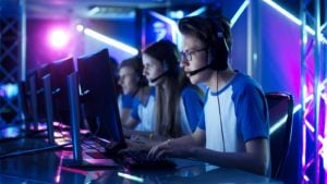 SKLZ stock A row of people wearing matching outfits and headsets play a video game together in a room with blue lighting.