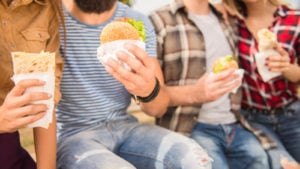 a group of people eating fast food, including cheeseburgers and fries