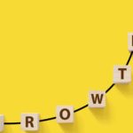 Wooden blocks spelling out "growth" form a steep upward arrow on a bright yellow background. growth stocks. Stocks to Double