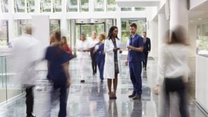 two doctors look over a piece of paper while standing in a hallway