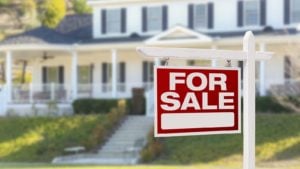 a large house has a For Sale sign out front