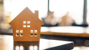 cardboard miniature house on table back-lit by sunlight through a window for IPOB stock story