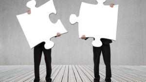 spac stocks two business people holding giant puzzle pieces, representing mergers and SPACs