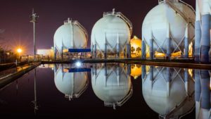 natural gas storage at night, storage facility reflected in pond