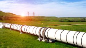 Momentum stocks: Natural gas pipeline through green field with blue sky above