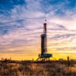 photo of large oil well infrastructure in a field at sunset