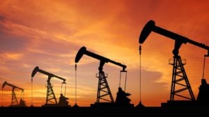 Image of an oil wells with an orange-red sky at dusk