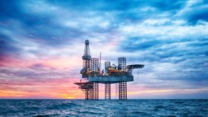 a picture of an oil rig in the middle of the ocean on a cloudy day representing energy stocks.