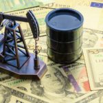 miniature oil barrel and oil well figures on top of stack of money