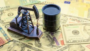 miniature oil barrel and oil well figures on a stack of money