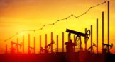 Illustration of oil pump jacks on sunset sky background to represent oil and gas stocks
