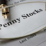 Glasses viewing penny stocks on a piece of paper