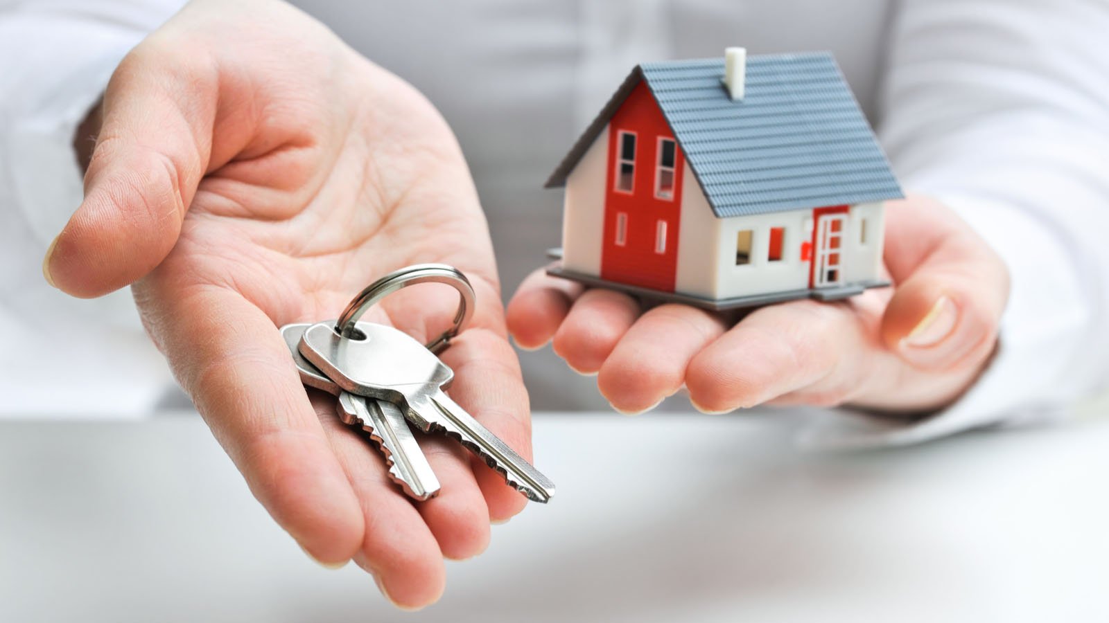 Hands holding a miniature house and keys