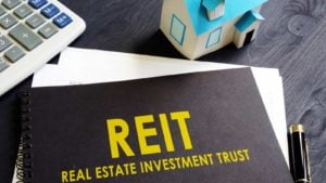 オフィスの机の上の黒いノートに不動産投資信託 (REIT)。