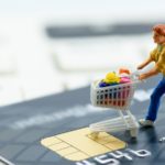 a figure of a shopper standing on top of a credit card. best retail stocks to buy in April