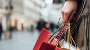 A close-up shot of a woman walking down the street with several paper shopping bags. ATER Stock