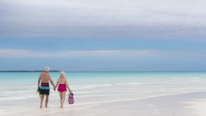 two people holding hands on an empty beach