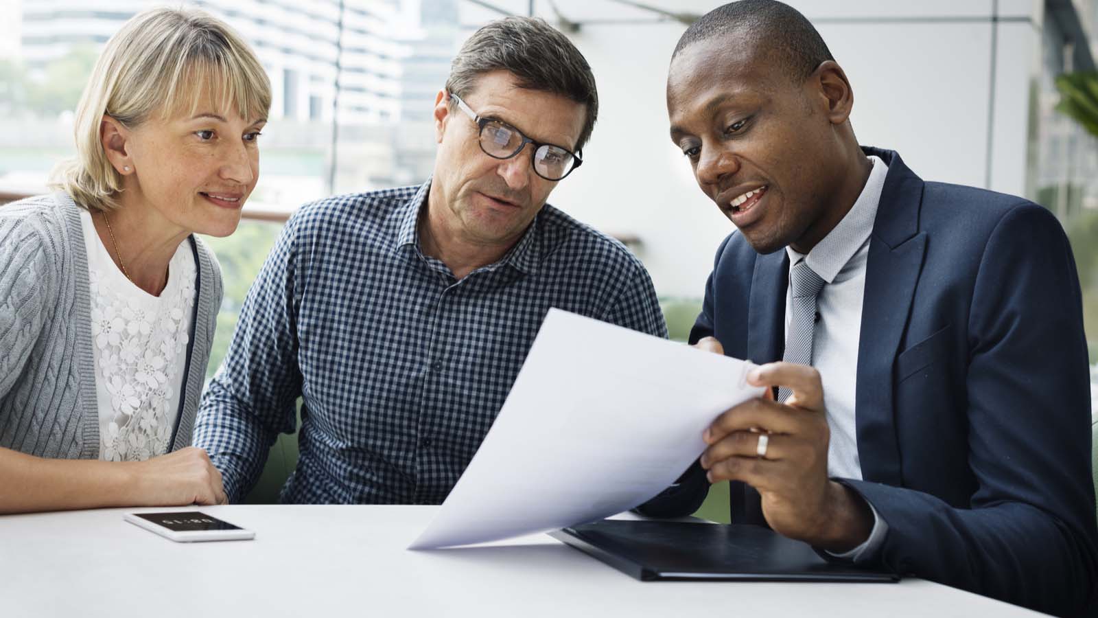 a financial planner showing a couple a piece of paper