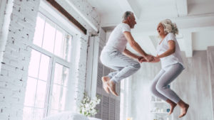 an elderly couple jumping up in a white household