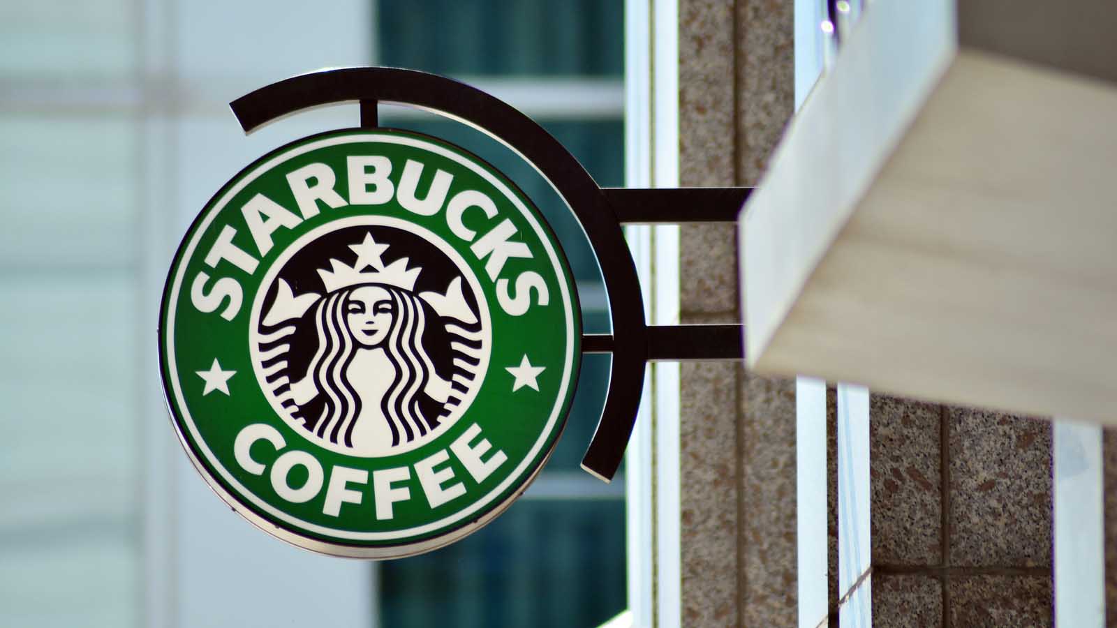 the Starbucks (SBUX) logo on a sign outside of a coffee shop