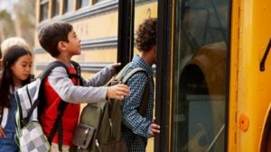 children boarding a school bus, representing Education Stocks to Buy