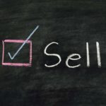 sell written on a chalkboard representing overvalued stocks to sell