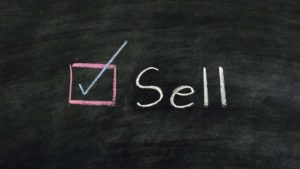 sell written on a chalkboard representing overvalued stocks to sell