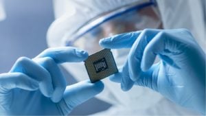 In Ultra Modern Electronic Manufacturing Factory Design Engineer in Sterile Coverall Holds Microchip with Gloves and Examines it. Semiconductor stocks to sell. Undervalued Semiconductor Stocks