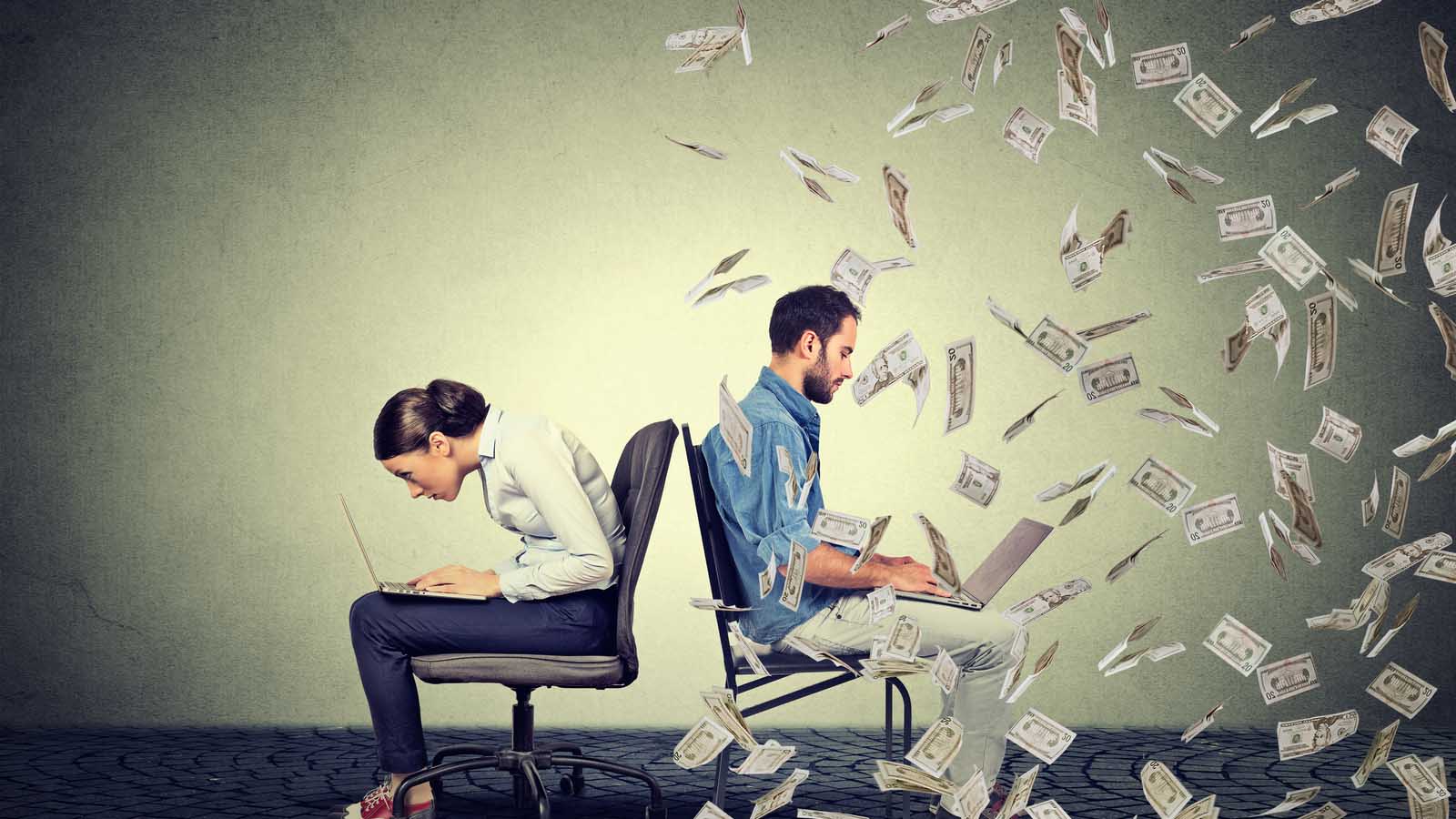 stocks to buy. two people in desk chairs with laptops. person on right side is being showered in dollar bills while person on left is hunching over their computer screen